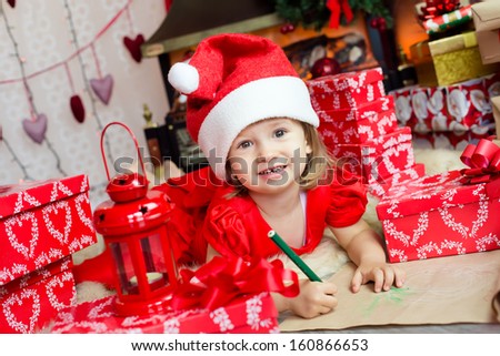 Smiling child in a cap of Santa Claus fill her wish list