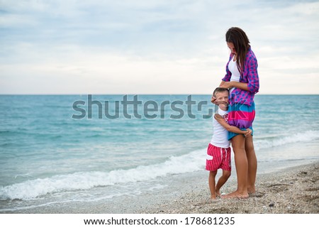 Mother with the son looking on something in the black-sea at the summer warm day
