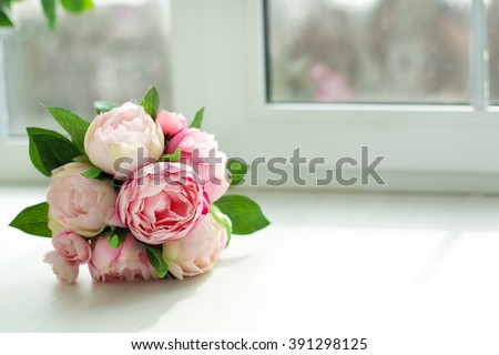 bouquet of peonies lies on a windowsill