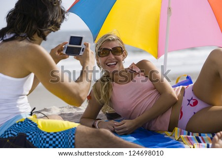 Adult friends making photos on the beach while sunbathing Adult friends making photos on the beach while sunbathing