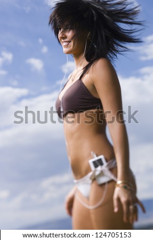 Young woman in bikini dancing against landscape