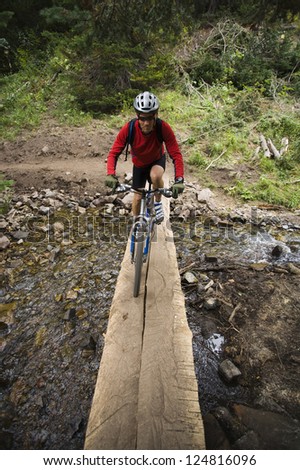Motion blur shot of a man biking trough river in forest