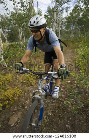 Motion blur shot of a man biking on path in forest