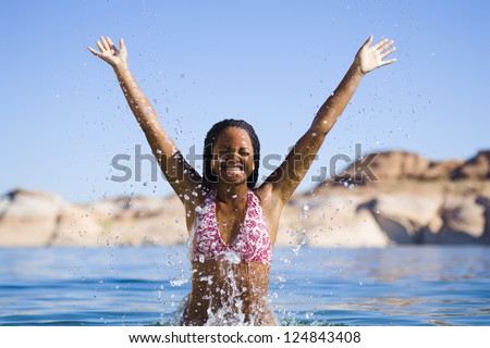 Happy African American woman jumping out of water