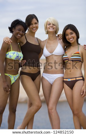 Four female friends in bikinis posing on seashore