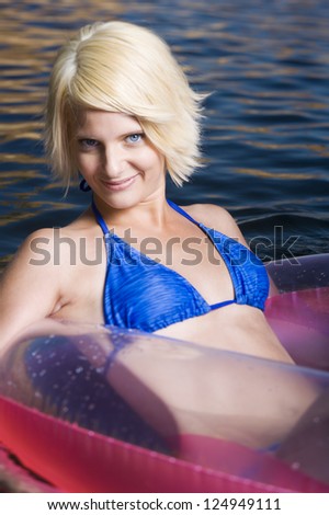 Young blonde woman floating in inflatable ring in sea