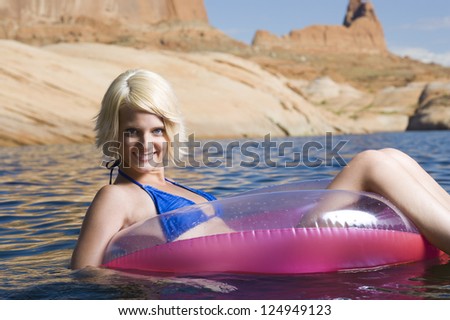 Young blonde woman floating in inflatable ring in sea