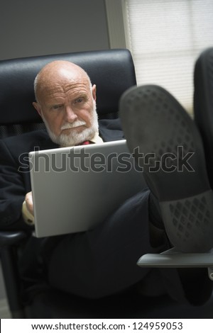 Elderly businessman working with laptop in office