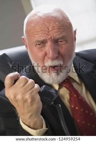 Portrait of angry elderly businessman holding landline