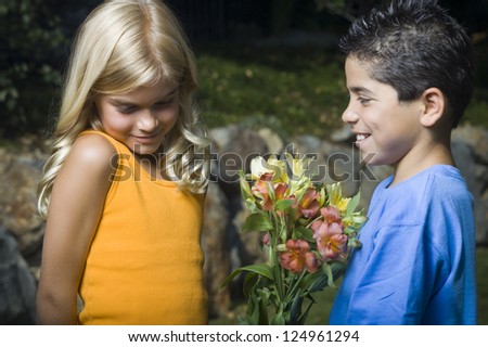 Portrait of little boy presenting flowers to girl