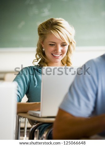 Girl looking at notebook computer in classroom.