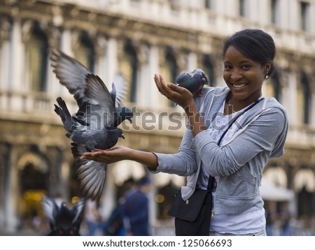 Woman in public square with pigeons smiling