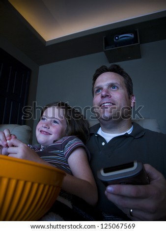 Father and daughter watching movie in home theater