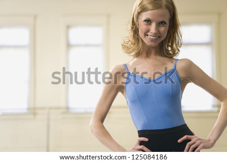 Young woman in aerobics dress posing and smiling in rehearsal room