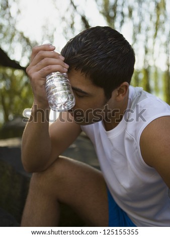 Male jogger cooling his forehand with a bottle of water