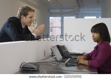 Young business man begging woman in office cubicle