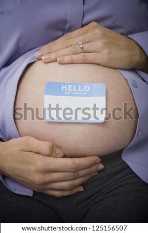 Closeup of pregnant belly with blank name tag