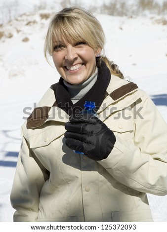 Woman in winter coat and gloves holding a bottle of water