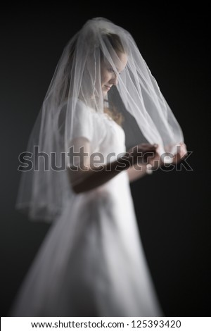 Side view of bride holding her wedding veil with shallow depth of field