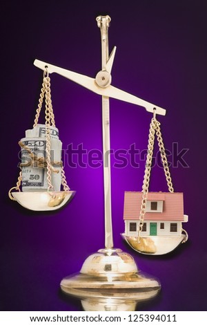Scale with money and model of a house over purple background