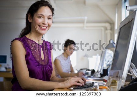 Hispanic woman working on computer at her desk
