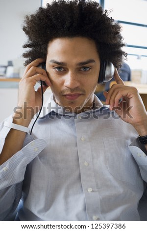 Young mixed race man listening music sitting in a chair