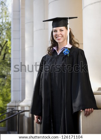 Female student standing in academic gown outdoors