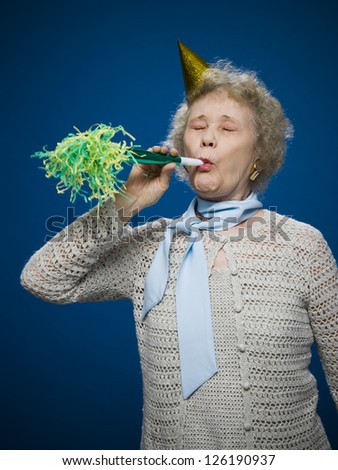Portrait of older woman with noisemaker and party hat
