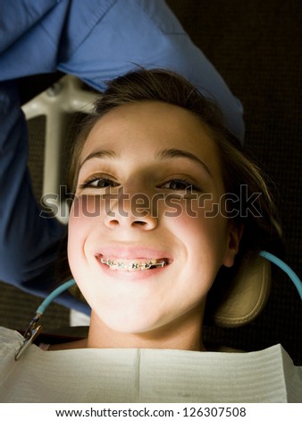 Portrait of happy girl with brackets sitting in dentist cabinet