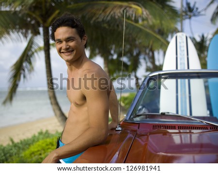 Portrait of a young man leaning against a car