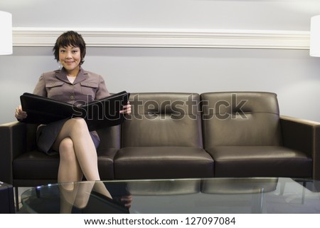 Portrait of a businesswoman sitting on a couch with a portfolio