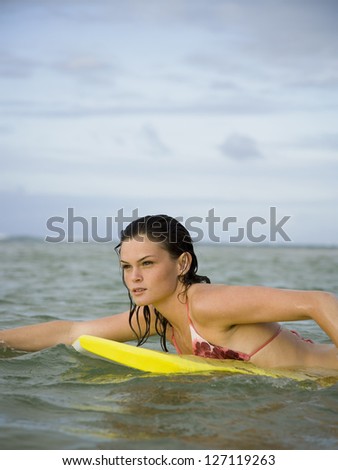 Profile of a teenage girl floating on a boogie board in the sea