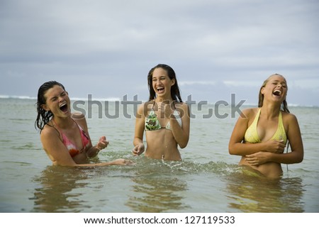 Motion blur shot of three teenage girls standing in the sea and laughing