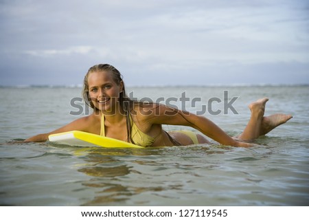 Teenage girl floating on a boogie board in the sea
