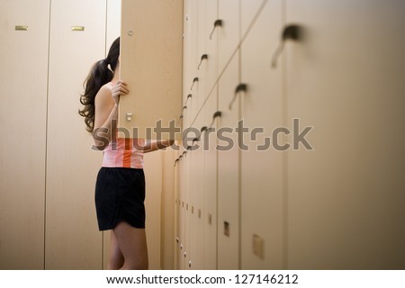 Profile of a young woman standing behind a closet door