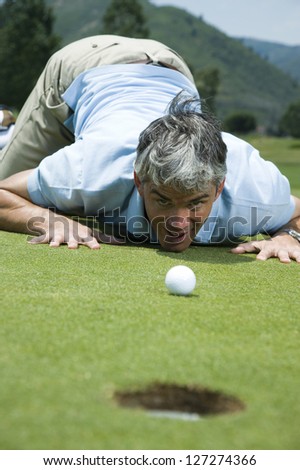 Man kneeling near a golf hole
