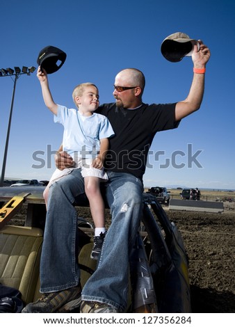 Father and young son waving ball caps in air