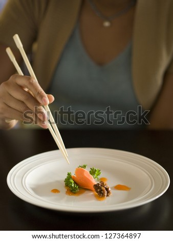 Woman eating small amount of delicious salad with chopsticks