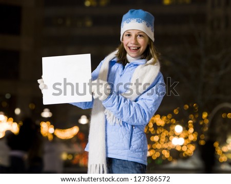 Girl with braces smiling outdoors in winter holding a blank board