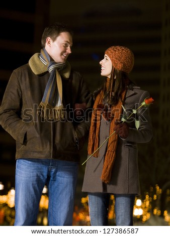 Man with woman holding rose in winter coat