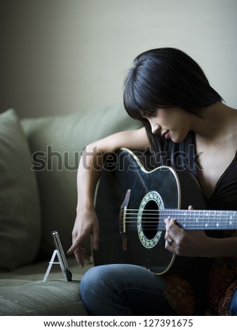Woman with acoustic guitar composing music