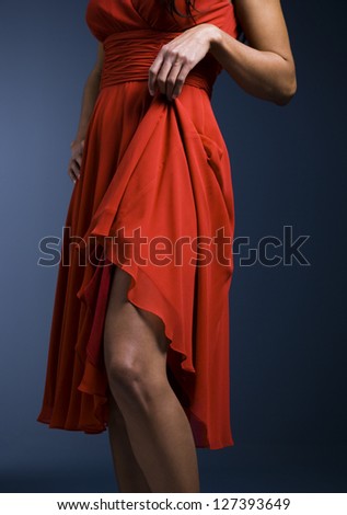Midsection view of woman with red dress exposing her leg