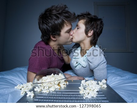 Young couple kissing in front of a computer