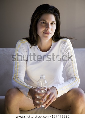 Woman sitting on sofa holding a bottle of water