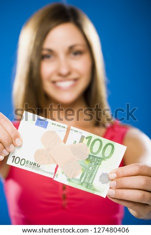 Close-up of a woman\'s hand with torn one hundred euro banknote with plastic strips