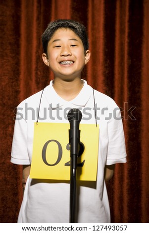 Boy standing at microphone and smiling with braces