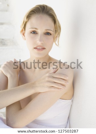 Woman leaning on wall with hands on shoulders