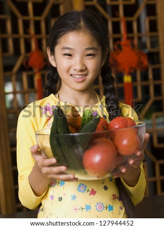 Girl holding bowl of vegetables smiling