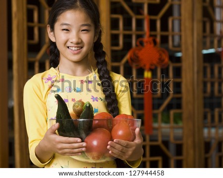 Girl holding bowl of vegetables smiling