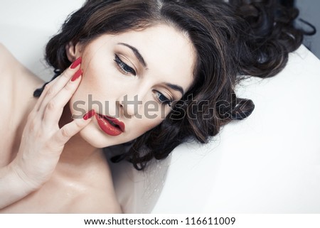 portrait of a beautiful brunette close-up with red lips and red lacquer on the nails